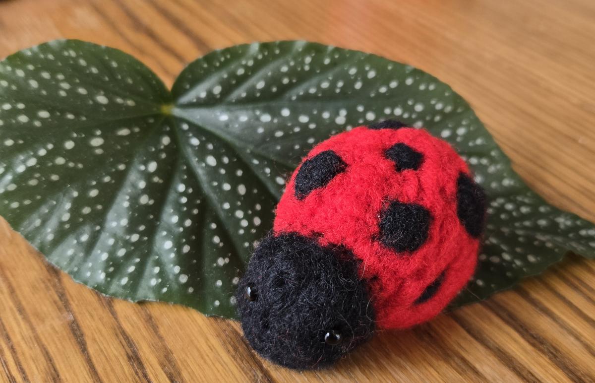 Image of a needle felted ladybug on a leaf.