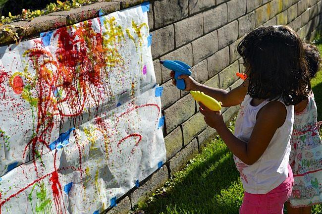 Child using squirt gun to paint mural